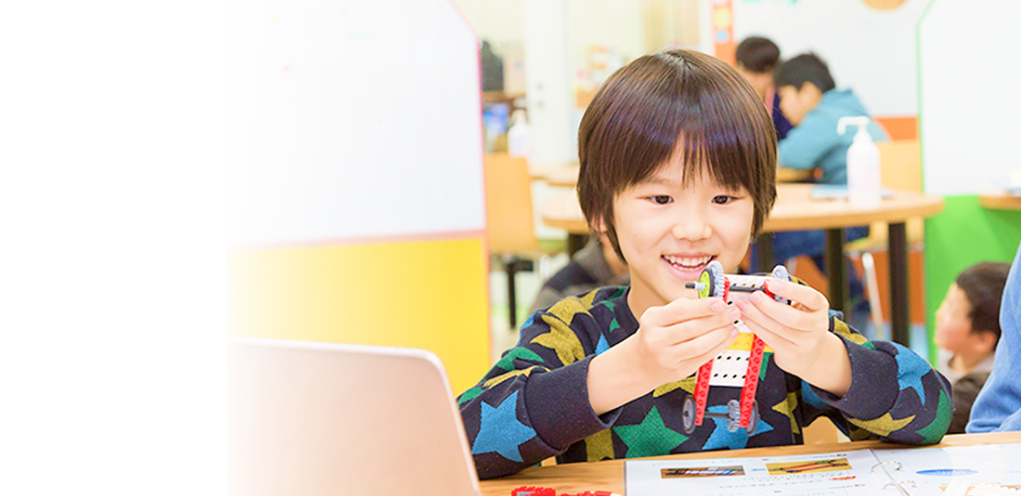 教室でロボット作品を手に笑顔の男の子