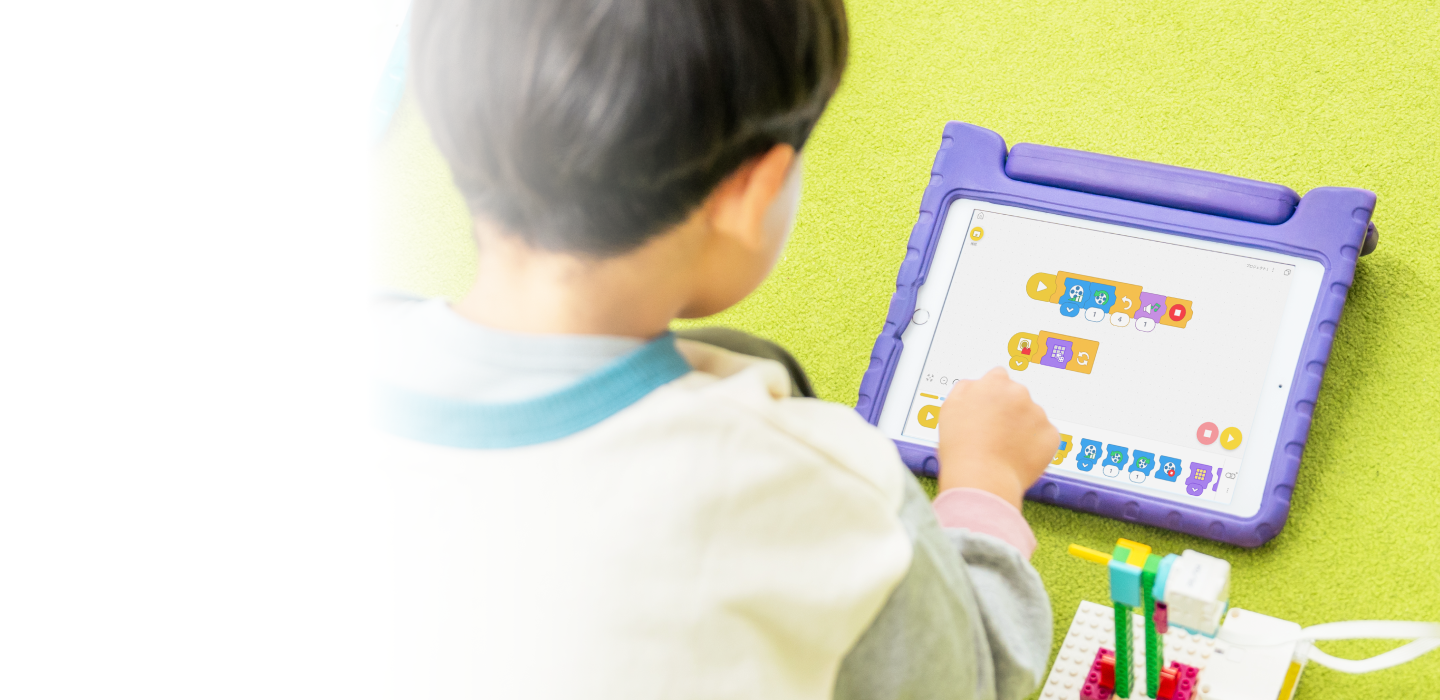 タブレットでScratchのプログラミングに取り組む子ども